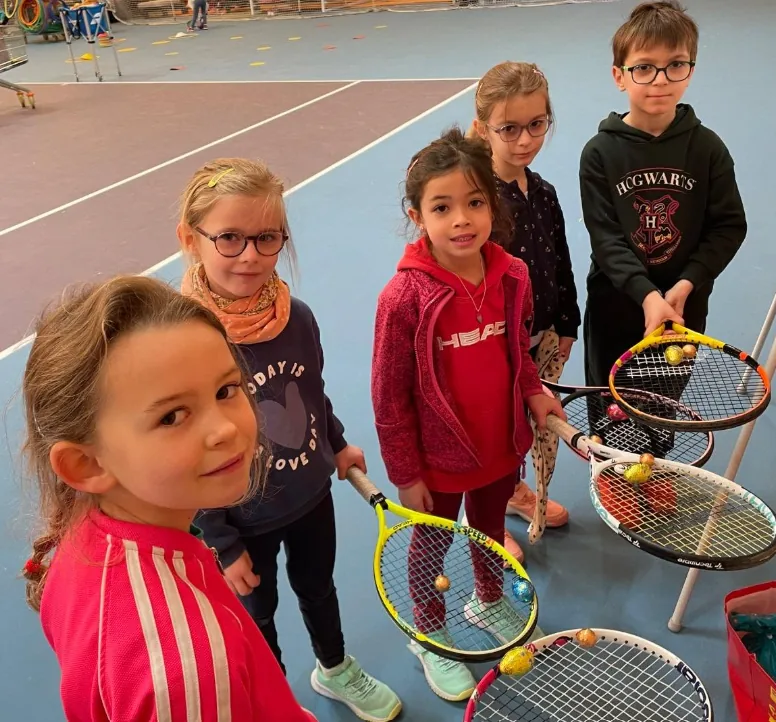 Des enfants de l’école de tennis, raquettes en main, sous la halle